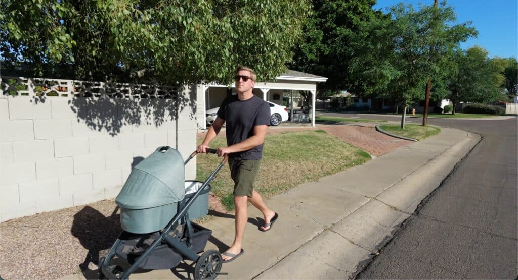 A man pushing an UppababyVista v2 down a suburban sidewalk